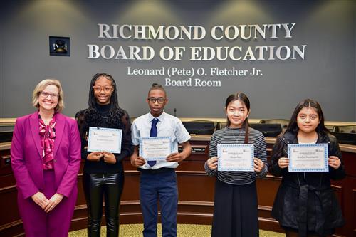 woman and four children holding certificates and smiling. 
